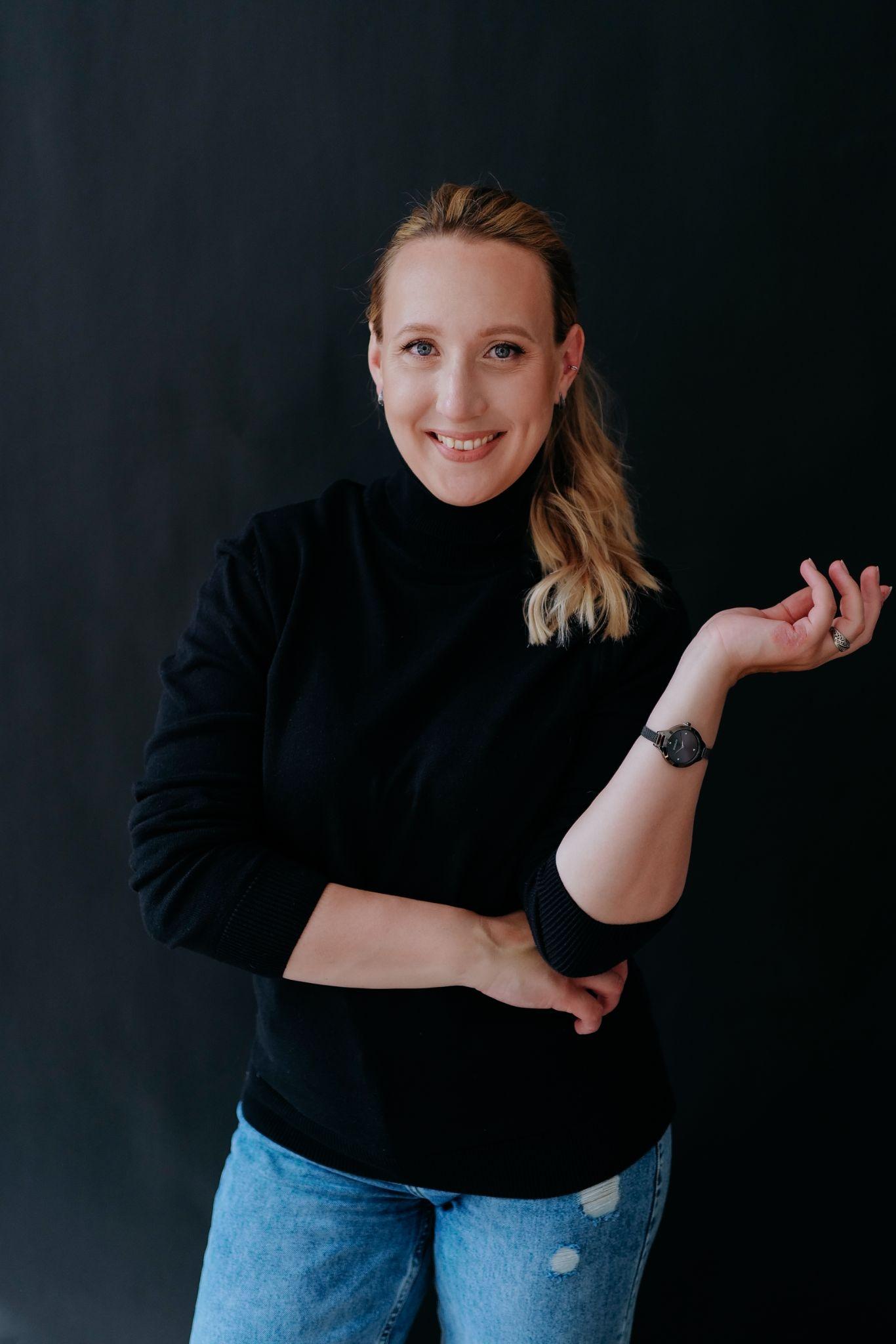 Anna Klevtcova recipient of the WildCats Professional Development Award wearing a black jumper and jeans standing in front of a dark background